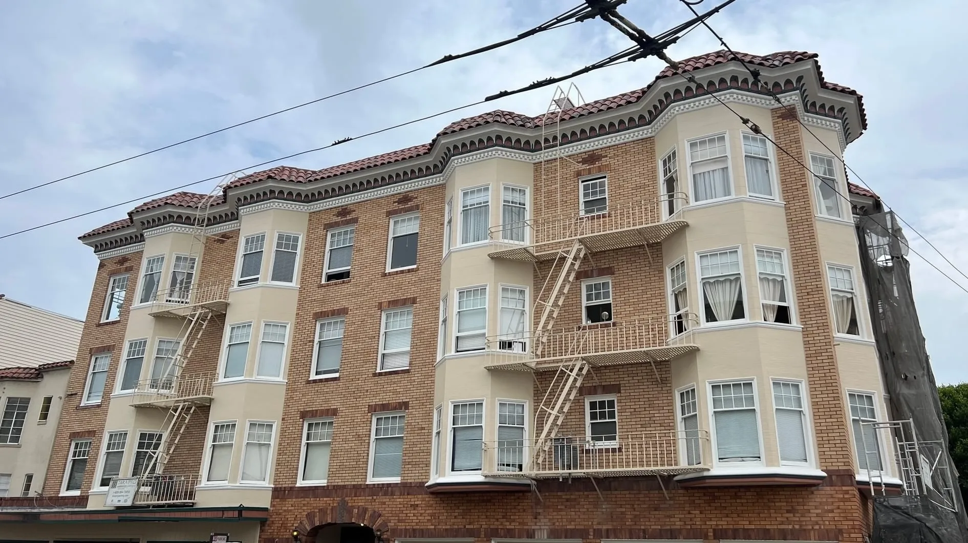 Corner view of the same San Francisco apartment building with completed cream paint, restored brick, trim and red tile roof