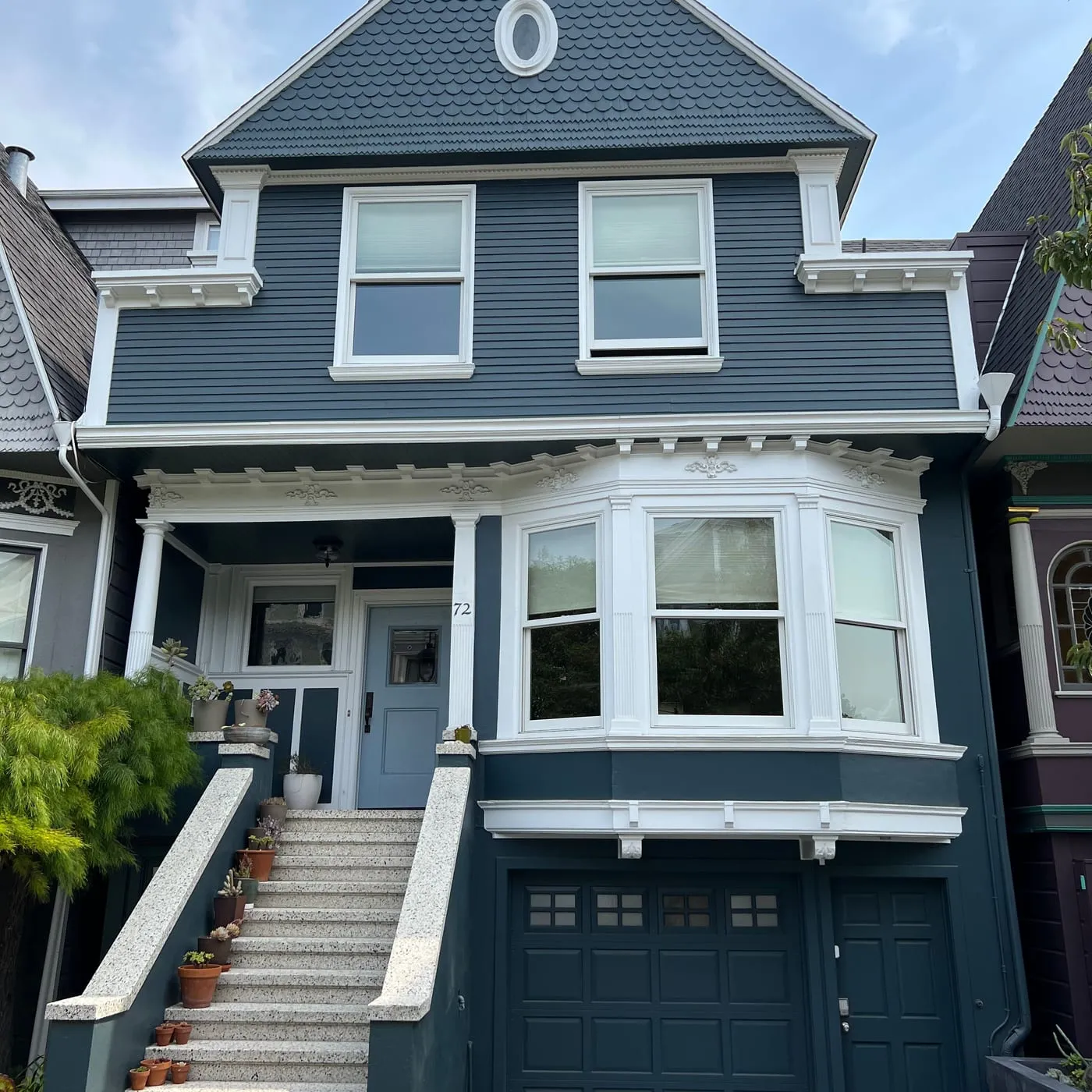 Slate-blue San Francisco Victorian with white bay-window trim and repainted garage door