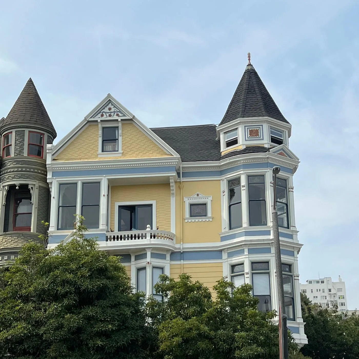 Yellow Victorian with a corner turret and dark shingle roof after exterior restoration