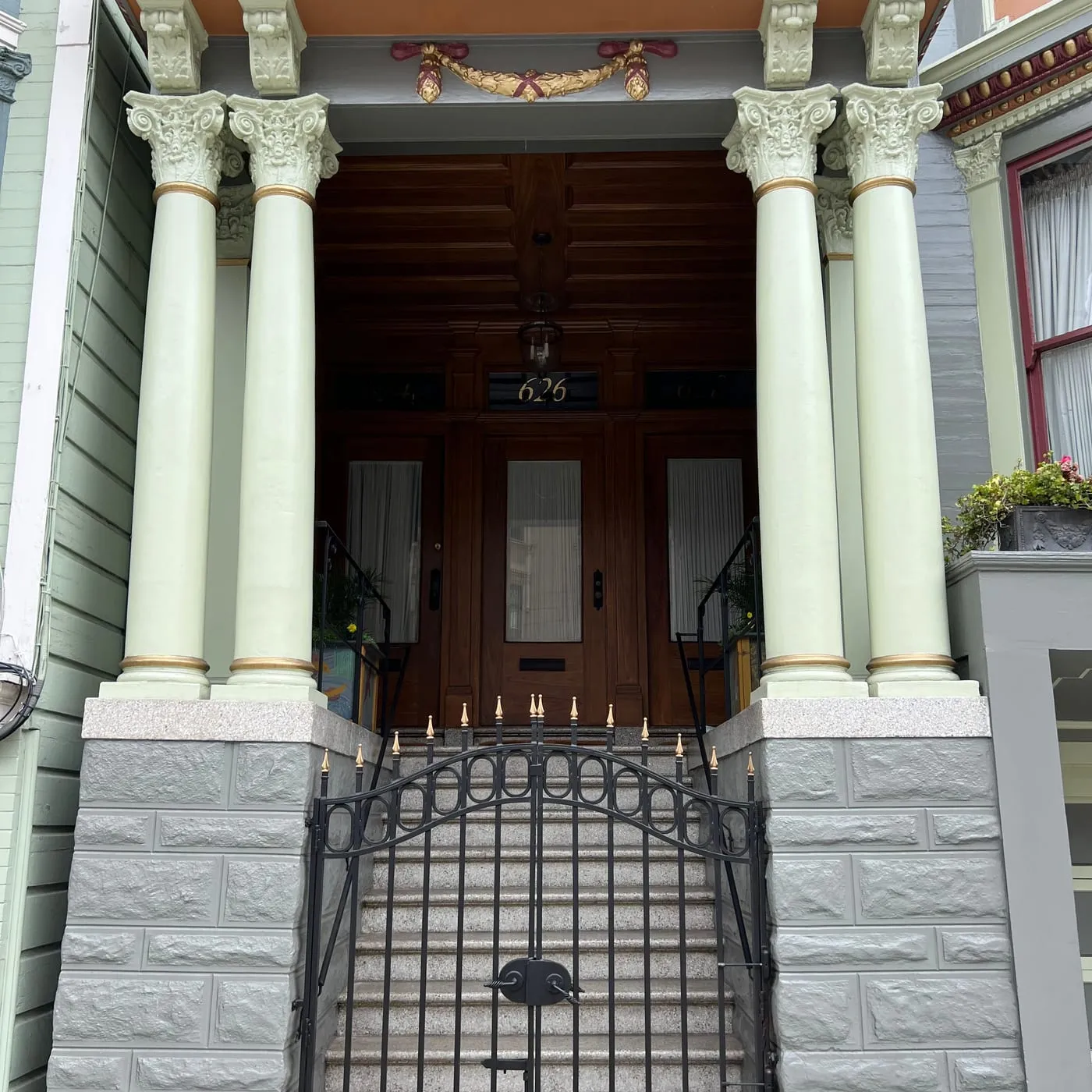 Grand San Francisco entry with cream painted columns, wrought-iron gate and restored wood doors